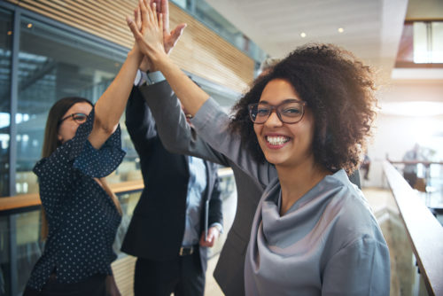 Smiling black businesswoman giving high five to ofiice team